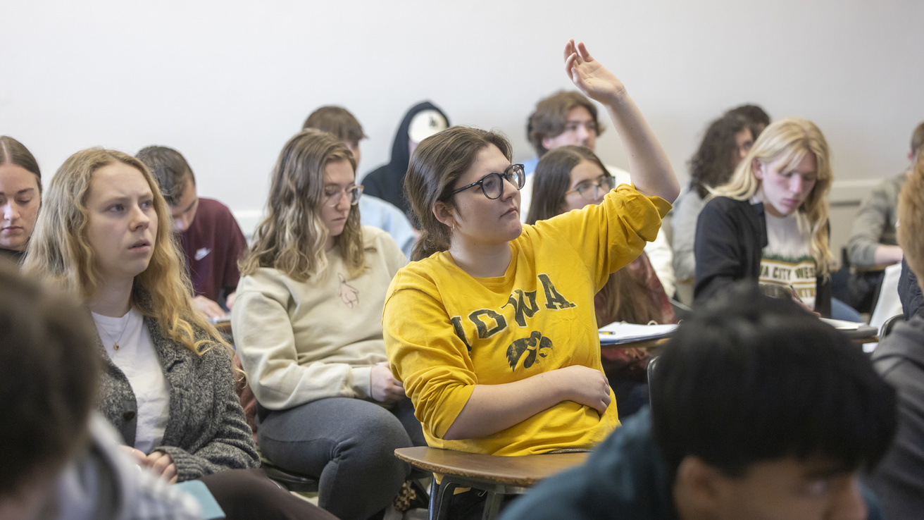 student wearing Iowa sweatshirt rasing her hand to anser questions in math class